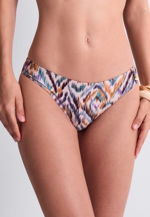 Le ventre d’une femme portant un bas de bikini à motifs violet, turquoise, orange et blanc sur un fond clair.