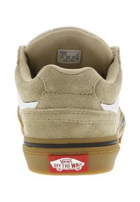 Chaussure de skate en suède tan avec des accents blancs, talon arrondi, semelle en caoutchouc gomme, et logo rouge "VANS OFF THE WALL" sur le talon.