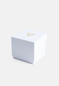Fehér, négyzet alakú texturált doboz, amelynek tetején arany háromszög logo található, csomagolás céljából tervezve.