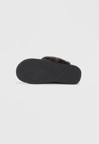 Black rubber slipper sole with raised text pattern. Soft upper material in a dark color, featuring a slightly rounded shape.