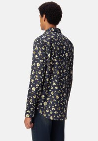 Camicia a maniche lunghe di colore blu navy con motivo floreale in crema e oro, dotata di un colletto classico e orlo curvo. Realizzata in tessuto leggero.