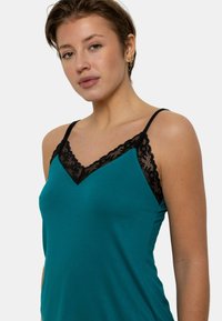 Débardeur bleu canard avec des détails en dentelle noire le long du décolleté en V. Design simple, tissu doux, fines bretelles réglables et coupe décontractée.