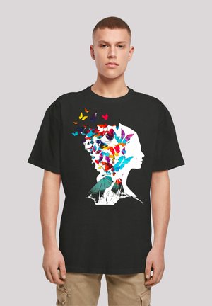 Black t-shirt featuring a graphic design of a profile silhouette filled with colorful butterflies in various shades and sizes.