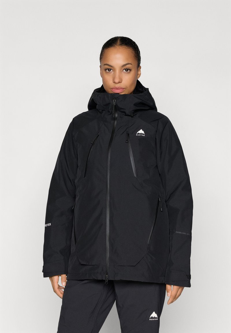 Melnā Gore-Tex jaka ar augstu apkakli, pilnu rāvējslēdzēju un regulējamu kapuci. Ietver divas rāvējslēdzēja sānu kabatas un logo uz krūtīm.