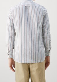 Camicia a maniche lunghe in tessuto leggero con righe verticali blu e rosse; presenta un colletto classico e polsini con bottoni.