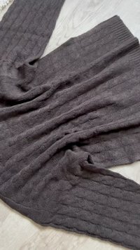 Σκούρο γκρι πλεκτό παντελόνι με σχέδιο πλέξης καλώδιο, απλωμένο επίπεδα σε ανοιχτό ξύλινο δάπεδο.