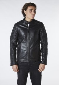 Chaqueta de cuero negra con detalles acolchados en los hombros, un collar alto y bolsillos con cremallera. La tela tiene una textura suave y un diseño ajustado.