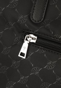 Borsa in tessuto nero con un motivo testurizzato, dotata di una zip con un tirante argentato e un dettaglio in pelle.