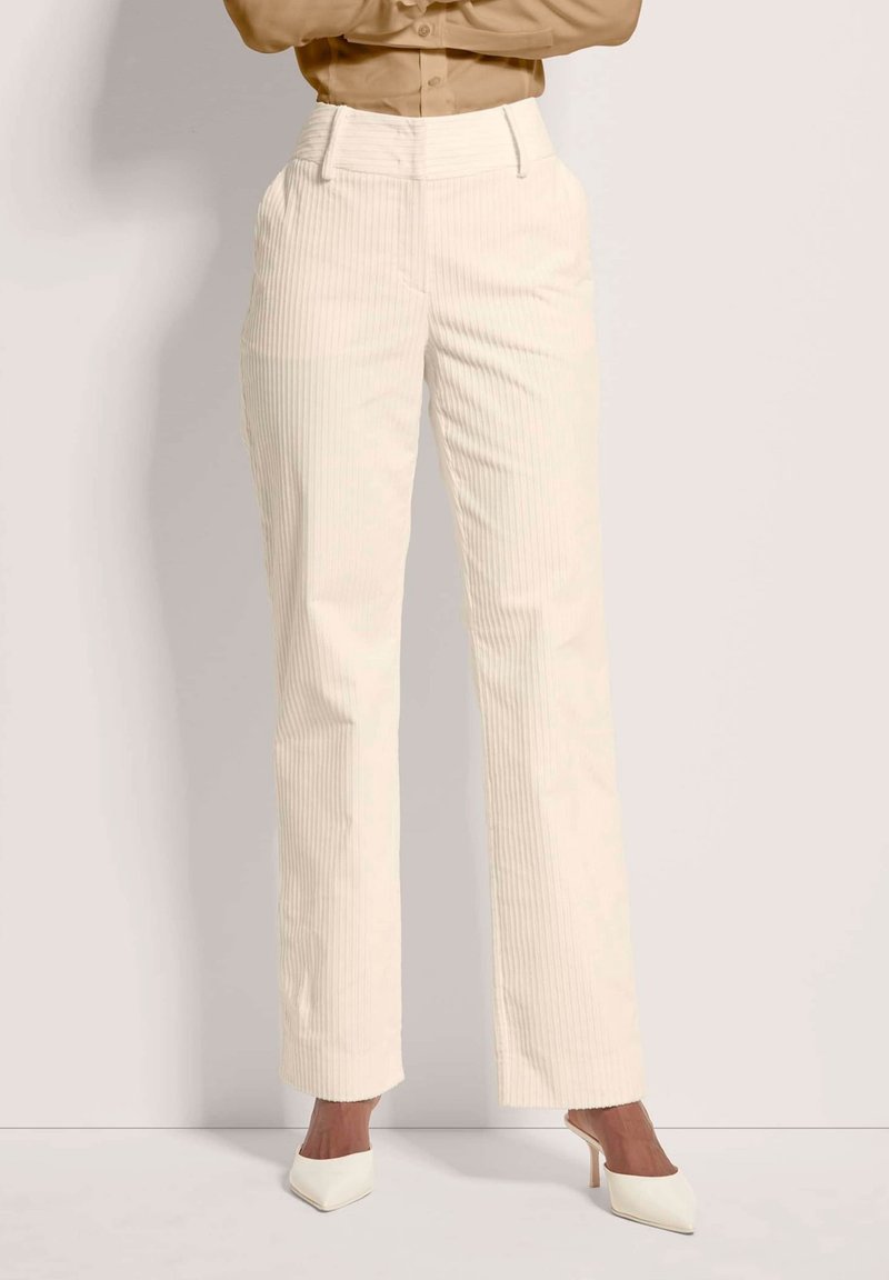 Crème, geribbelde broeken met een hoge taille en rechte pijpen. Gecombineerd met witte puntige hakken, met een subtiele textuur en een op maat gemaakt ontwerp.