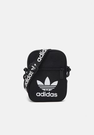 Czarna torba na ramię Adidas z białym logo trefoil, przednią kieszenią na zamek i regulowanym paskiem z powtarzającym się nadrukiem Adidas.