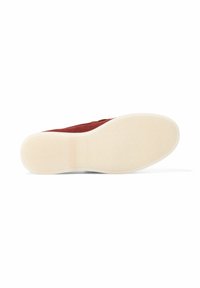 Zapatilla de ante rojo con suela de goma blanca. La suela presenta un patrón texturizado para mayor agarre. Diseño minimalista sin logotipos visibles.