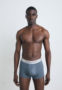 Grijze stretchkatoenen boxershorts met een witte Calvin Klein tailleband, met een gladde textuur en een aansluitend ontwerp.