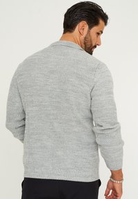 Grauer Strickcardigan mit strukturiertem Finish, gerippten Bündchen und Saum. Mit Schalkragen und langen Ärmeln, von hinten betrachtet.