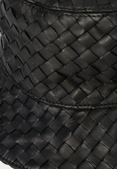 Close-up van zwart leer met een geweven patroon en gedetailleerde stiksels langs de naad.