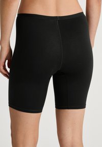 Zwarte katoenen boxershorts met een snug fit, voorzien van een gladde textuur en een elastische tailleband, die net boven de bovenbenen eindigen.