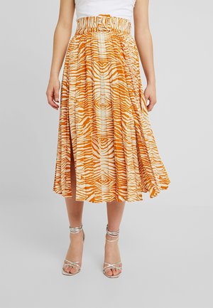 Midi-nederdel i orange og creme med mønster, forsynet med en samlet talje og en siden splitt, parret med sølvfarvede strop sandaler.