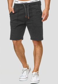 Shorts gris foncé en tissu, dotés d'une taille élastique avec cordon de serrage à motif contrastant et de deux poches avant.