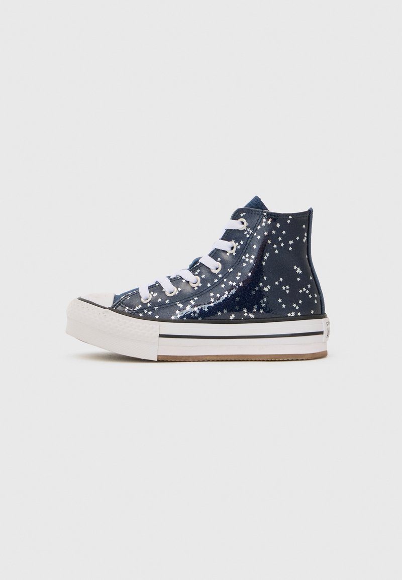 Zapatillas altas de color azul marino con un acabado brillante. Decoradas con patrones de estrellas blancas, con cordones blancos y suela de goma.