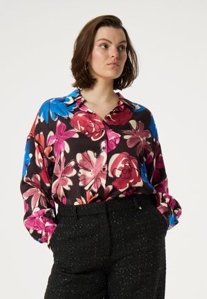 Bloemige zijden blouse met een donkere achtergrond, versierd met grote roze, rode en blauwe bloemen. Zachte textuur en een knoopsluiting aan de voorkant.