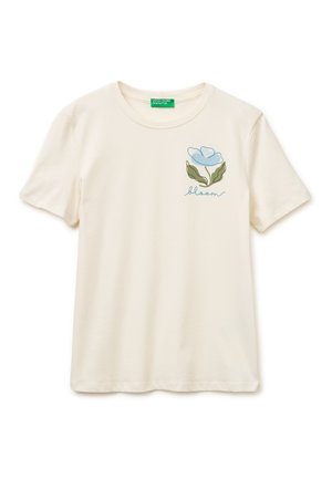 Camiseta cremosa de manga corta con cuello redondo, con gráfico de flor azul y texto "bloom" en el lado izquierdo del pecho.