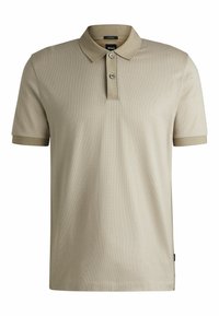 Polo shirt beige à manches courtes, tissu texturé, patte de boutonnage à trois boutons et accents de col et de poignets contrastants.