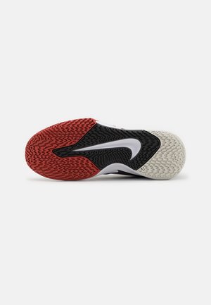Podeszwa buta sportowego z czerwono-czarno-białym wzorem bieżnika, z dużym białym logo „swoosh” na środku.