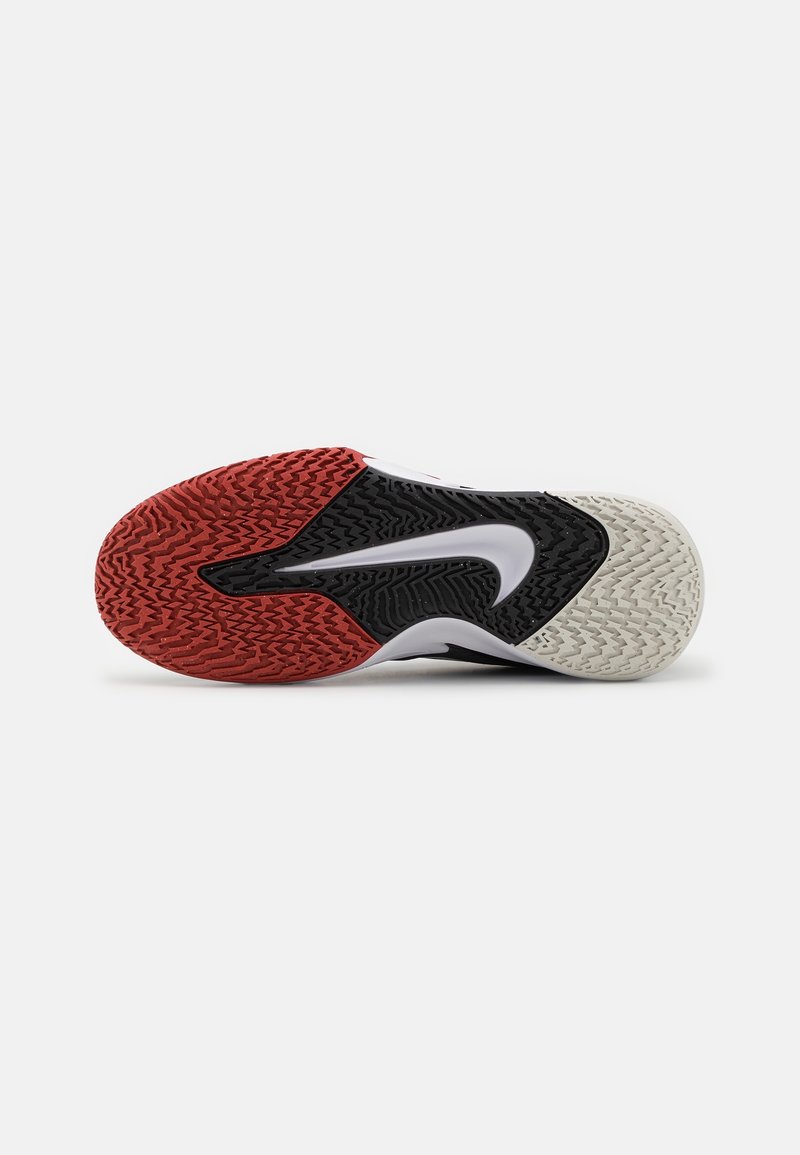 Semelle de chaussure de sport avec un motif rouge, noir et blanc, avec un grand logo swoosh blanc au centre.