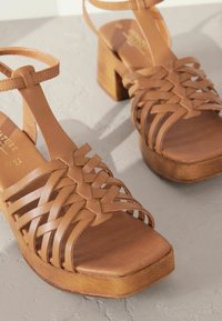 Bruine leren platform sandalen met een geweven bandontwerp, vierkante neus en een houten hak, met een gladde textuur.