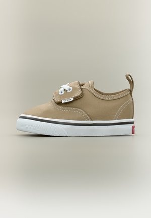 Μπεζ παιδικό αθλητικό παπούτσι Vans με λευκή καουτσούκ σόλα, σχέδιο βέλκρο με κορδόνια και ταινία έλξης στη φτέρνα σε απλό φόντο.