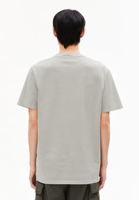 Lichtgrijze katoenen T-shirt met korte mouwen, een ronde halslijn en een relaxte pasvorm. Naaddetails rond de randen, achteraanzicht weergegeven.