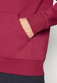 Bordeaux sweatshirt med en kængurulomme, ribbede manchetter og kant. Blød stofstruktur med synlige syninger.