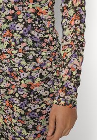 Vestido de flores de manga larga con fondo negro y flores multicolores en naranja, morado y verde. Detalle texturizado y fruncido a lo largo de las mangas.