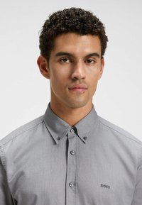 Camisa gris de botones con cuello estructurado, logo bordado "BOSS" y tejido texturizado con un acabado suave.