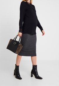 Svart långärmad topp med spetsdetaljer, grå ribbad blyertskjol, svarta klackboots och väska med ormskinnsmönster.