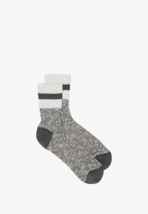Gestrickte graue Socken mit einem strukturierten Design. Weißer gerippter Bund mit zwei dunkelgrauen Streifen. Dunkelgraue Akzente an Ferse und Zehen.