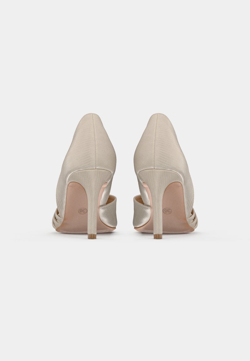 Zapatos de tacón alto beige con un diseño de punta afilada, fabricados en un tejido texturizado. Presentan un lado con corte y un tacón delgado y alto.