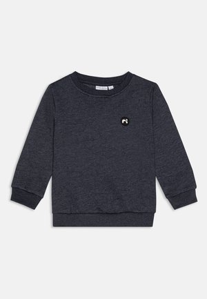Felpa grigio scuro con maniche lunghe, colletto a giro, e polsini a coste; presenta un piccolo logo circolare ricamato nero sul petto.