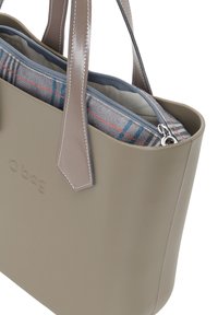 Taupefarbene Kunststofftasche mit grauen Ledergriffen, ausgestattet mit einem internen Reißverschlussfach, das mit einem karierten Stoff in Grau- und Blautönen ausgekleidet ist.