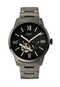 Montre automatique noire avec quincaillerie argentée, chiffres romains, dos transparent mettant en valeur le mouvement, et bracelet en acier inoxydable.