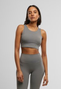Sivi crop top i set tajica visokog struka izrađeni od glatkog, rastezljivog materijala. Ima okrugli izrez i minimalistički dizajn.