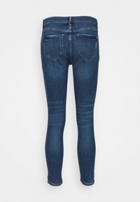 Tajta jeans i mörkblå denim med en slät yta, fem fickor och en klassisk midja. Bakom finns två sydda fickor.