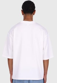 Hvid oversized kortærmet t-shirt med rund halsudskæring. Har blødt bomuldsstof og en glat tekstur. Enkel, minimalistisk design.