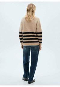 Pull en tricot beige avec des rayures noires horizontales, coupe décontractée, manches longues, associé à un jean en denim bleu, présenté de dos.
