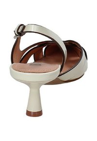 Sandalo con tacco color crema dal puntale arrotondato, con cinturino alla caviglia e un tacco elegante e affusolato, caratterizzato da dettagli marroni lungo i bordi.
