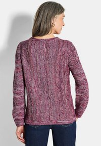 Maglione lavorato a maglia in tonalità di rosa e viola con un motivo a onde testurizzato. Presenta maniche lunghe e un collo rotondo con polsini a costine.