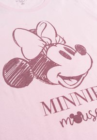 T-shirt in cotone rosa con un'illustrazione grafica della testa di un personaggio dei cartoni animati con un fiocco. Il testo recita "MINNIE" in lettere in grassetto sottostante.