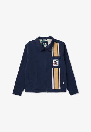 Marineblauwe jas met ritssluiting en beige-witte verticale strepen aan de rechterkant, met een patch van een zwarte schorpioen en rode vlammen op het borstzakje.