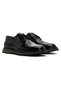 Chaussures habillées en cuir noir avec bout rond, design à lacets, semelle texturée, et légères accents striés le long du bord.