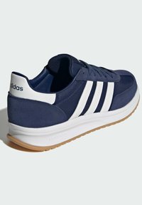 Marinträna sneakers i marinblått med vita accenter. Har en slät textilöverdel, tre vita ränder och en gummisula med ett strukturerat mönster.