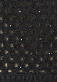 Tissu en dentelle tricotée noire avec un motif de losanges ouvert, orné de petites perles noires, sur un fond lisse.